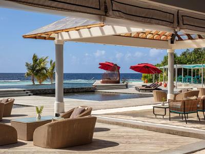 Taras z miejscami do siedzenia, basenem i widokiem na ocean w słoneczny dzień