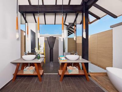 Bagno moderno con due lavandini, vasca autoportante e vista sul cielo aperto.