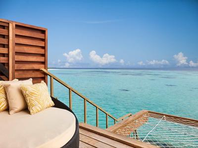 Letto rotondo su terrazza in legno con vista sul mare turchese e cielo azzurro.