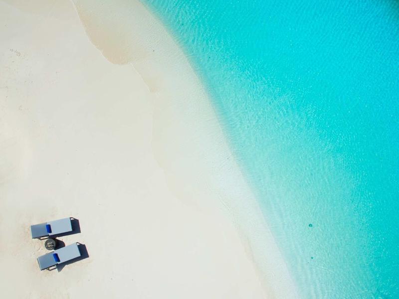 Due sdraio su sabbia bianca accanto ad acqua turchese trasparente sulla spiaggia