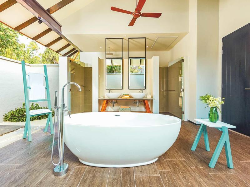 Vasca da bagno freestanding su pavimento in legno con vista esterna e design moderno.