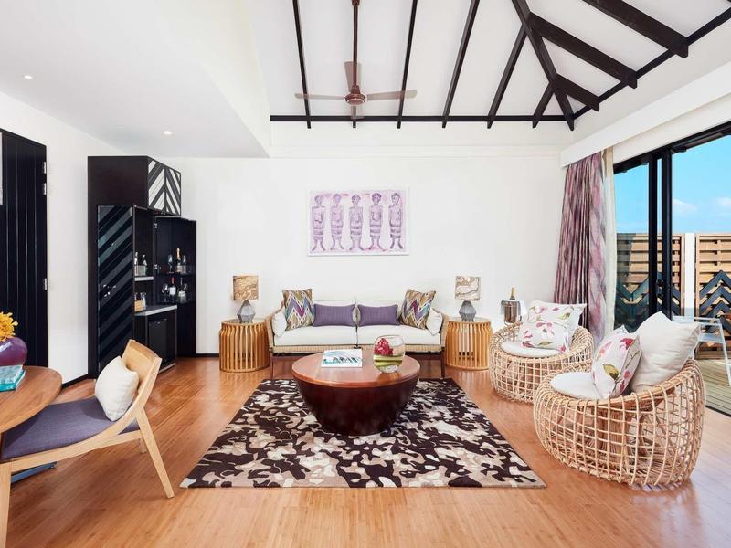 Soggiorno luminoso con pavimento in legno, comode poltrone in vimini e ampia finestra con vista sulla città.