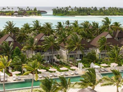 Luxuriöse Villen umgeben von Palmen und Pools auf einer tropischen Insel.