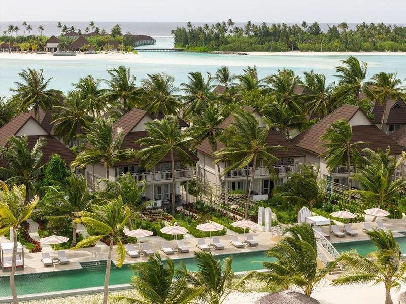 Ville di lusso circondate da palme e piscine su un'isola tropicale.