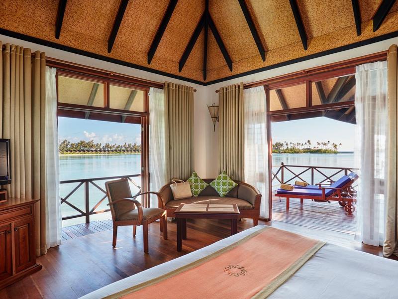 Interno di un bungalow sull'acqua con vista sulla laguna e zona salotto esterna.