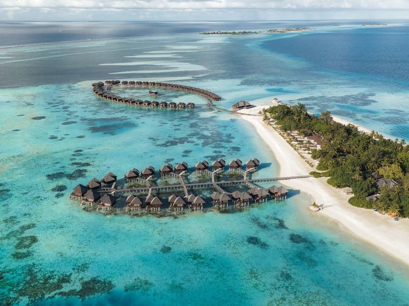 Resort su un'isola con bungalow sull'acqua in acque turchesi limpide e spiagge di sabbia bianca.
