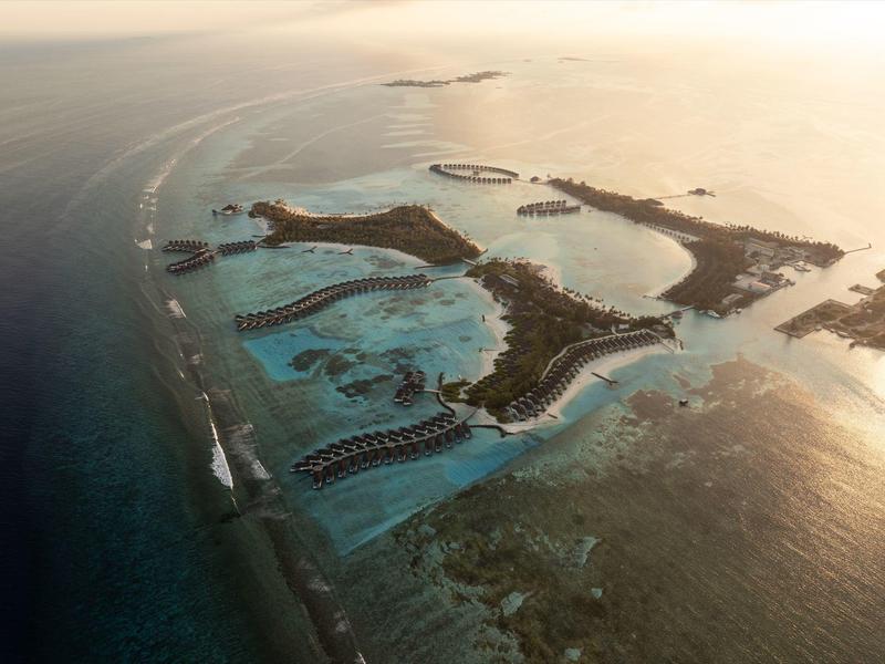 Vista aerea di un'isola tropicale con lagune, spiagge sabbiose e resort nell'oceano.