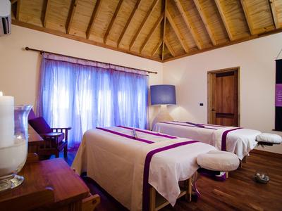 Zimmer mit zwei Massageliegen, Holzboden und Decke, weichen Vorhängen und entspannter Atmosphäre