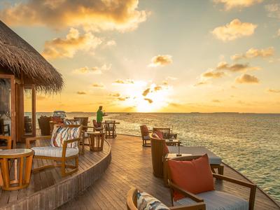 Sonniger Hotelbalkon mit Stühlen und Blick auf das Meer bei Sonnenuntergang.