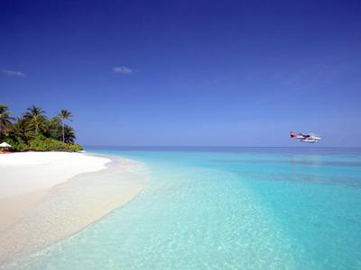 Weißer Sandstrand mit klarem türkisfarbenem Wasser und klarem blauem Himmel.