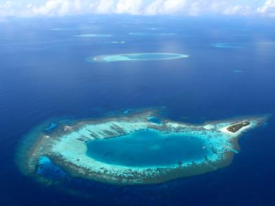 Luftaufnahme einer Lagune mit kleinen Inseln und klarem blauem Wasser.