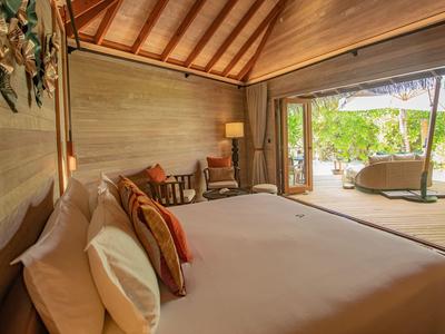 Gediegenes Schlafzimmer mit Holzdecke, großem Bett und Blick auf Terrasse und Garten.