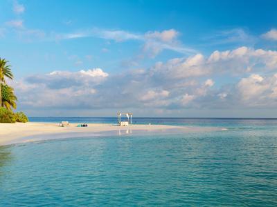 Strand mit weißem Sand, Palmen und klarem blauem Meer unter blauem Himmel mit Wolken