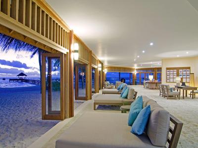 Offener Strandclub mit Liegen und Kissen direkt am Sandstrand bei Sonnenuntergang.