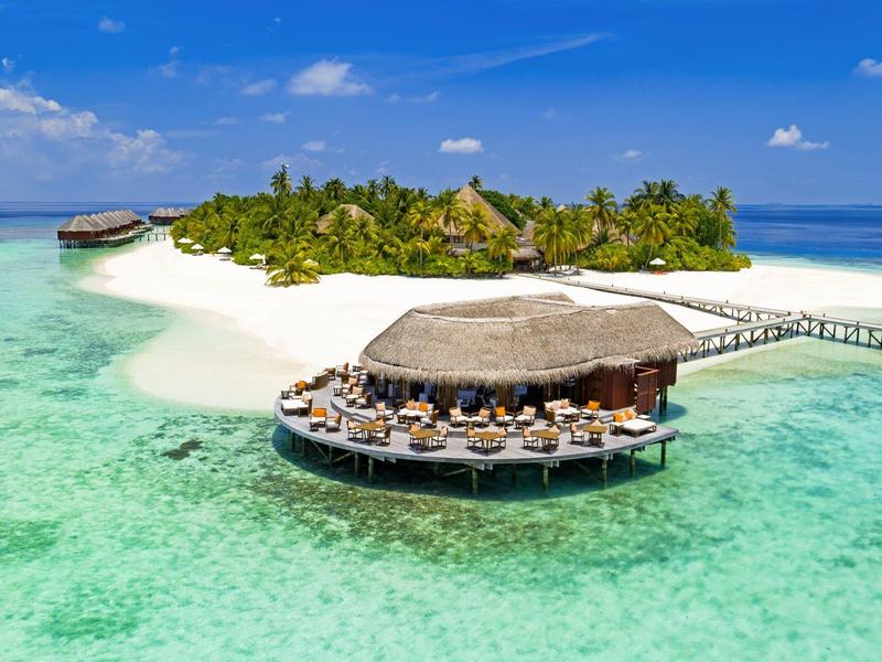 Insel mit tropischem Strand, kristallklarem Wasser und Überwasser-Bar mit Sitzplätzen.