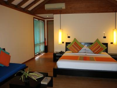 Modernes Schlafzimmer mit Holzbalkendecke, Doppelbett, orangenen und grünen Kissen, Hängelampen und gemütlicher Sitzbank.