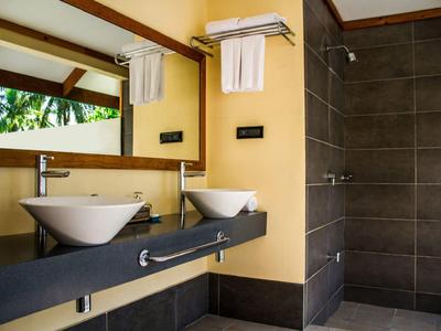 Moderne Badezimmer mit zwei weißen Waschbecken, großem Spiegel und Dusche mit dunkelgrauen Fliesen.