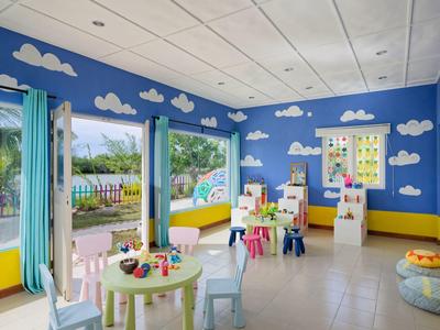 Kinderzimmer mit blauen Wänden, weißen Wolken, bunten Möbeln und Blick auf einen Garten.