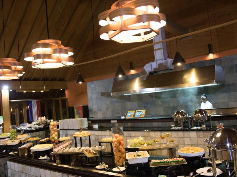 Buffet mit vielfältigen Speisen in einem modern beleuchteten Restaurant mit Holzdecke.
