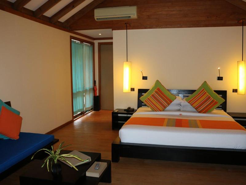 Modernes Schlafzimmer mit Holzbalkendecke, Doppelbett, orangenen und grünen Kissen, Hängelampen und gemütlicher Sitzbank.