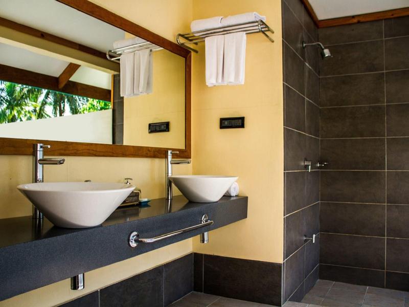 Moderne Badezimmer mit zwei weißen Waschbecken, großem Spiegel und Dusche mit dunkelgrauen Fliesen.