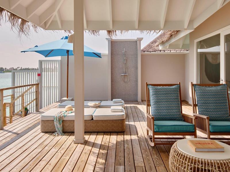 Gemütlicher Holzdeckbereich mit Liegestühlen und Außendusche am Wasser.