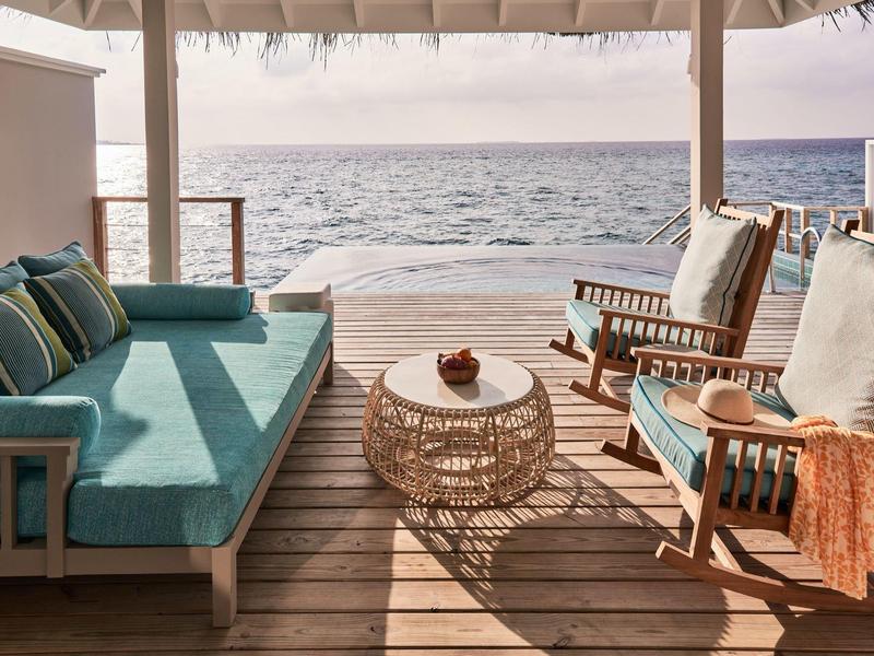 Terrasse mit gemütlichen Sitzmöbeln und Blick auf das Meer bei Sonnenuntergang.