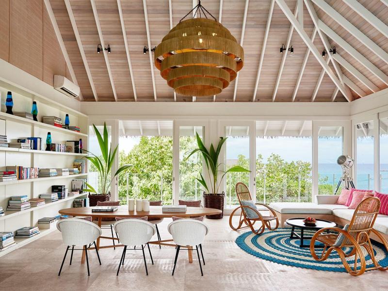 Ein heller Wohnbereich mit runden Sitzgelegenheiten, Pflanzen und Blick auf den Ozean.