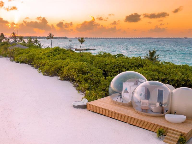 Strand mit Sonnenuntergang und transparenten Kapselbetten am Meer.
