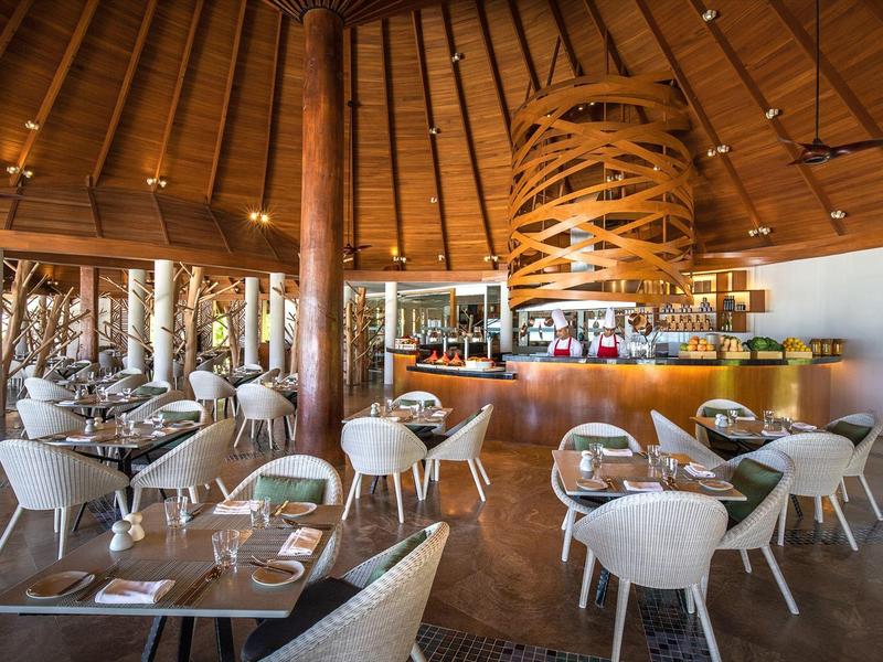 Przestronna restauracja hotelowa z drewnianym sufitem, nowoczesnymi stołami i wygodnymi krzesłami.