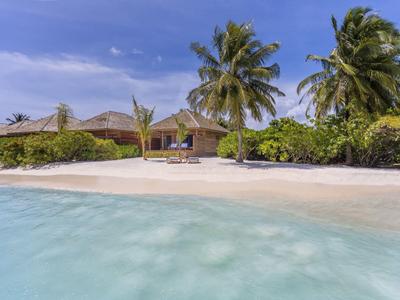 Strandbungalow mit Palmen und weißem Sand am klaren, blauen Meer.