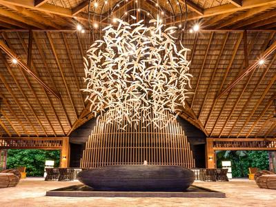 Ampia hall con struttura del soffitto in legno alta e lampadario moderno illuminato