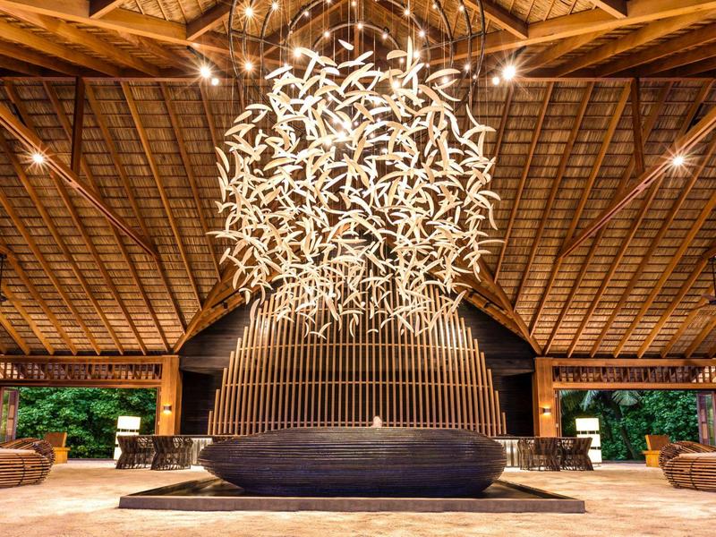 Ampia hall con struttura del soffitto in legno alta e lampadario moderno illuminato