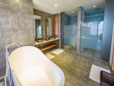 Baño moderno con bañera independiente, lavabo doble y ducha de vidrio en tonos cálidos.