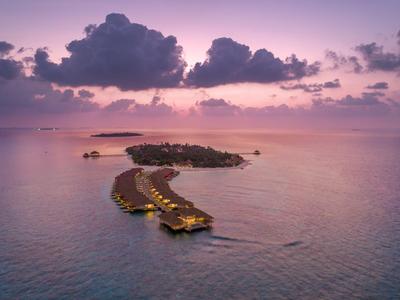 Bungalows auf Wasser mit Beleuchtung bei Sonnenuntergang im Meer.