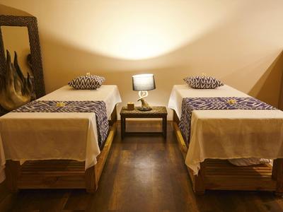 Dwa pojedyncze łóżka z białą pościelą i poduszkami obok małego stolika z lampą.