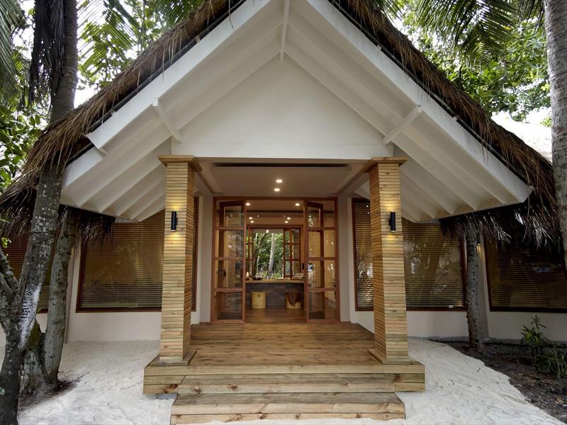 Wejście do tropikalnej drewnianej willi z schodami otoczone palmami i piaskiem.