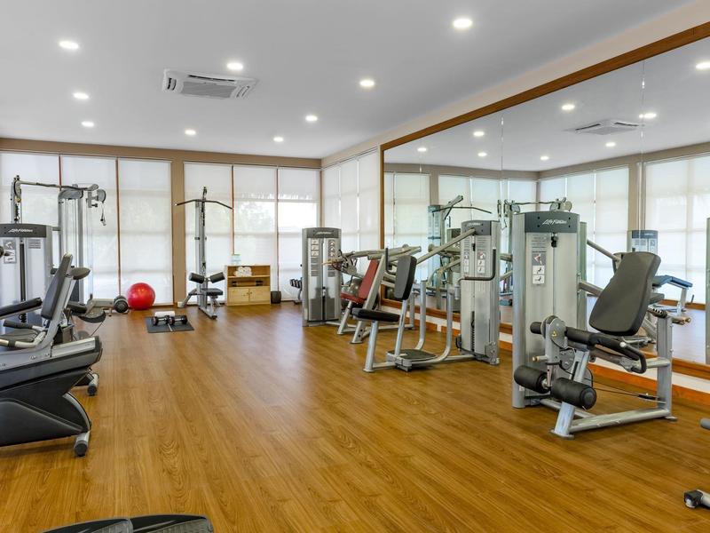 Przestronna siłownia z nowoczesnym sprzętem i drewnianą podłogą w hotelu.