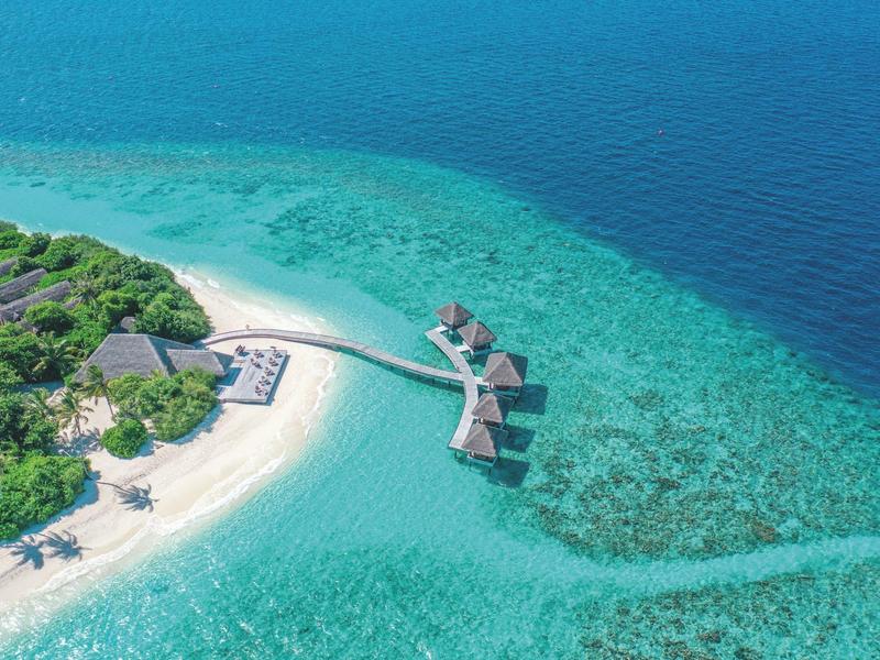 Zdjęcie z lotu ptaka wyspy z białą piaszczystą plażą i willami nad wodą w przejrzystym turkusowym morzu.