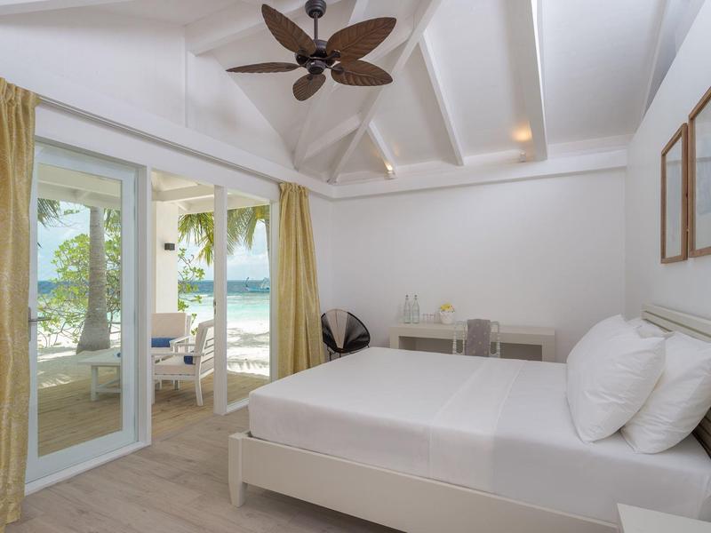 Helles Schlafzimmer mit Doppelbett, Deckenventilator und Zugang zur Terrasse mit Meerblick.