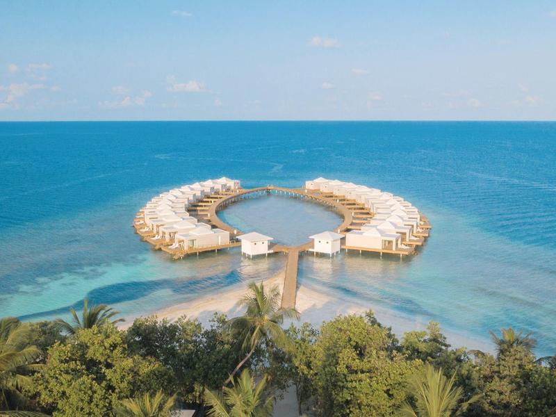 Luftaufnahme von zwei halbkreisförmigen Piers, die ins Meer hinausragen, umgeben von Palmen.