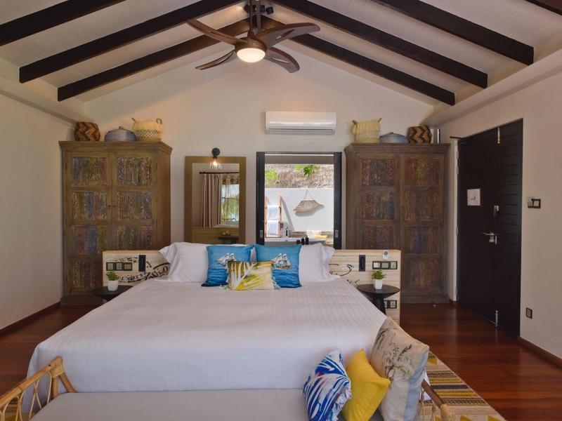 Chambre avec grands placards, lit confortable et poutres en bois au plafond dans une chambre d'hôtel.