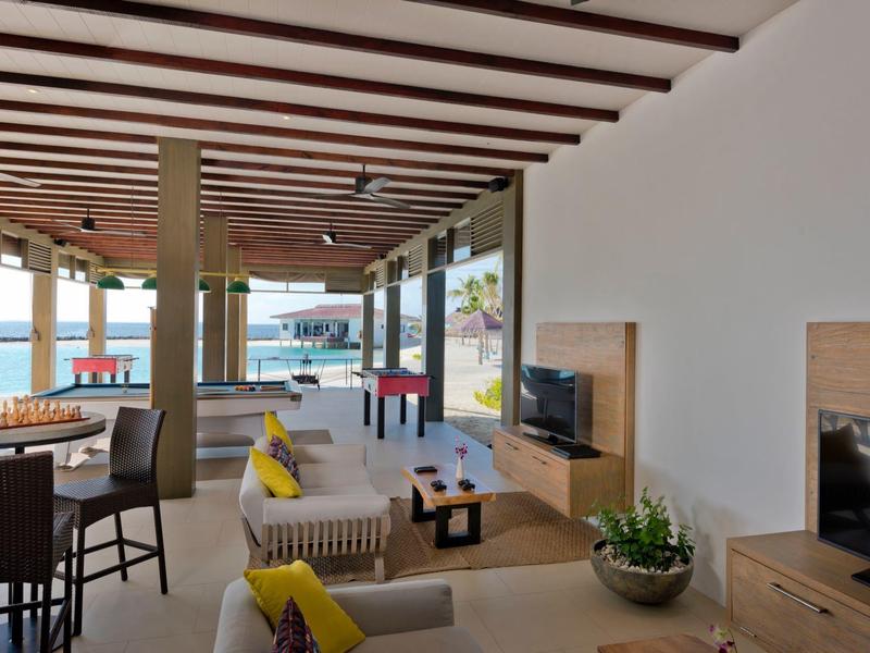 Espace lounge d'hôtel moderne avec sièges, TV et vue sur la mer à travers de grandes fenêtres