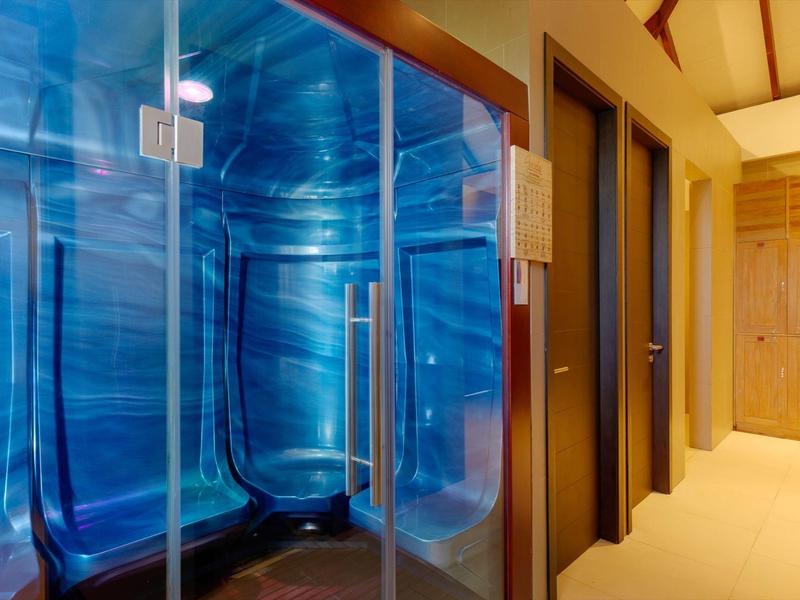 Sauna à vapeur bleue avec porte en verre dans un couloir avec d'autres salles de sauna.