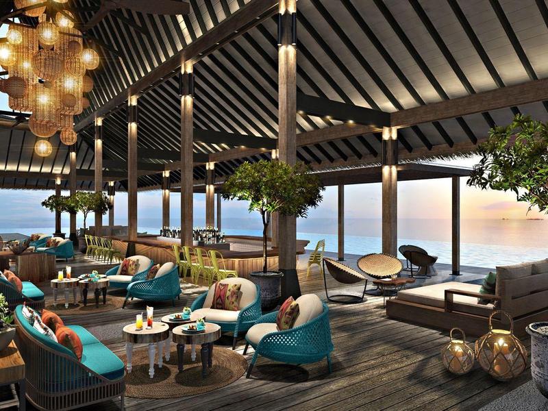 Espace lounge ouvert d'hôtel avec sièges confortables, arbres et vue sur la mer au coucher du soleil.