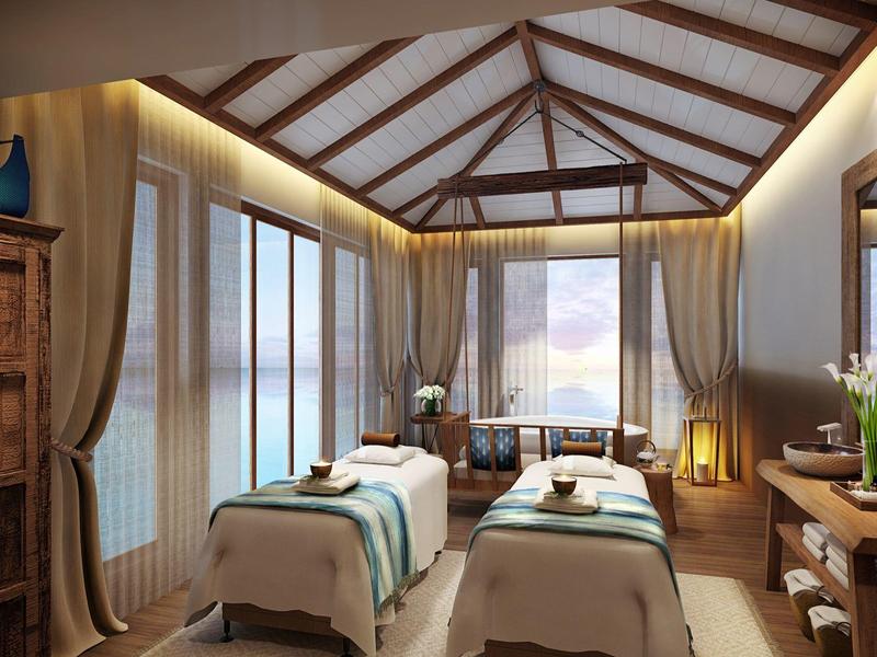 Chambre de spa confortable avec deux tables de massage et grandes fenêtres donnant sur la mer.