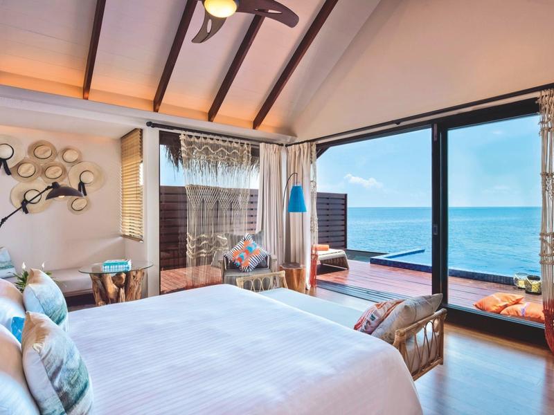 Chambre d'hôtel de luxe avec grand lit, fenêtres panoramiques et vue sur la mer
