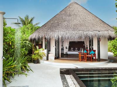 Bungalow de baño con techo de paja, muebles de madera y piscina privada en entorno tropical.