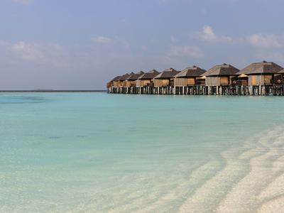 Überwasserbungalows am türkisfarbenen Meer mit weißem Sandstrand.