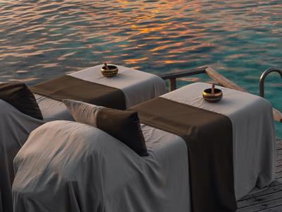 Cómodo conjunto de asientos junto al agua con mesas, café y vista al agua tranquila al atardecer.